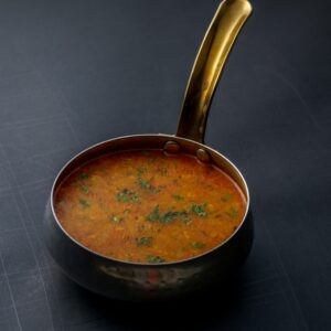 A close-up shot of Indian dal garnished with herbs in a copper pot, offering a taste of traditional cuisine.